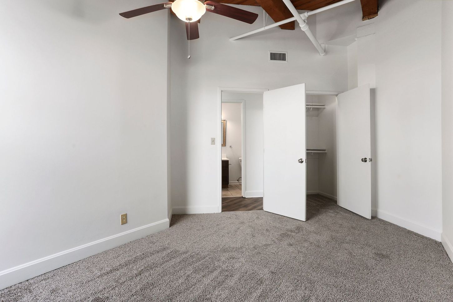 An empty bedroom with a ceiling fan and a closet.