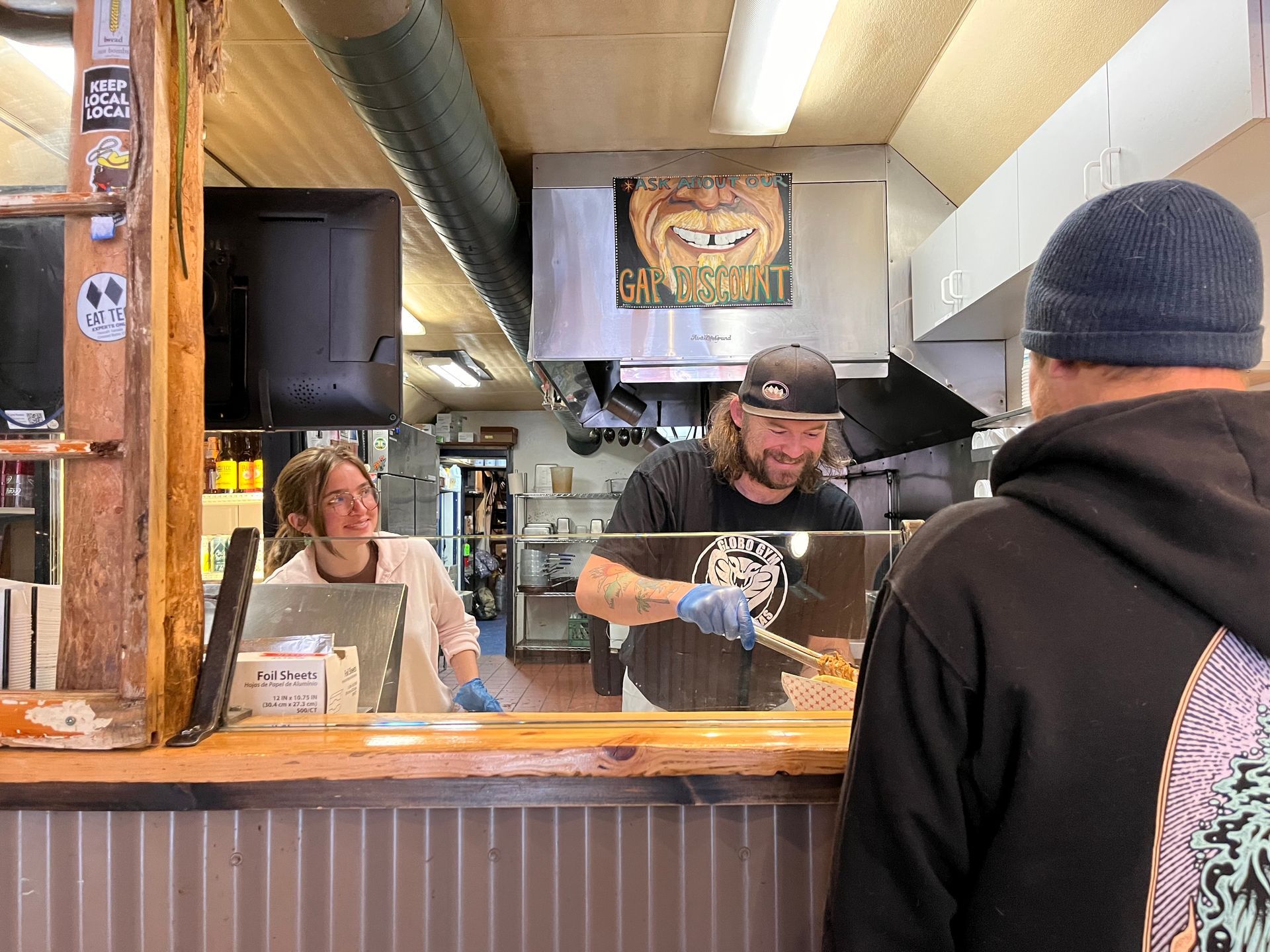 a man in a black hoodie is standing in front of a sign that says gary 's grill