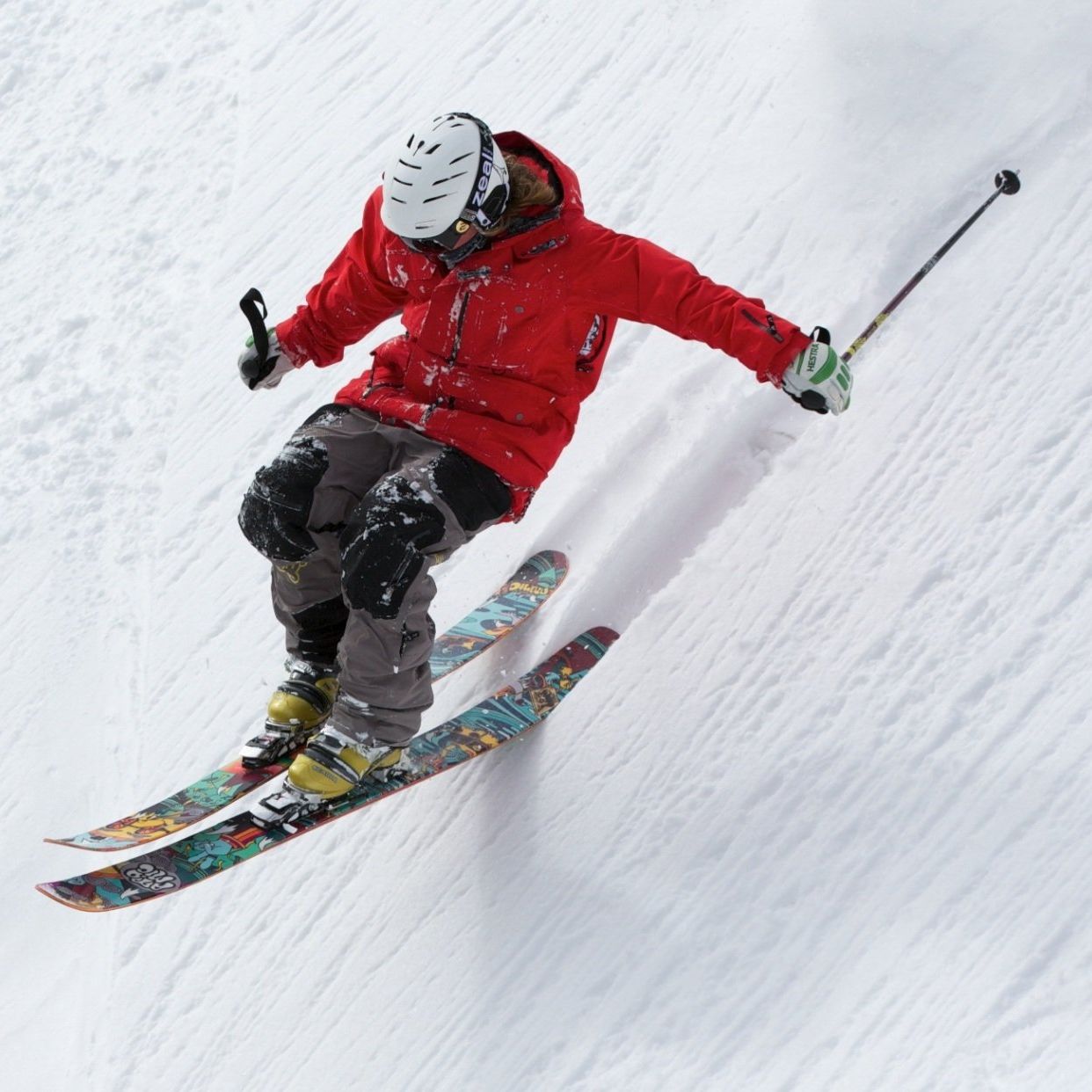 A person in a red jacket is skiing down a snowy hill
