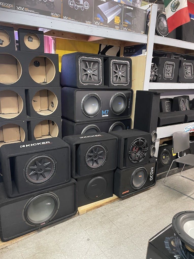 Stacks of black car subwoofers in a retail setting, with empty subwoofer boxes to the left.