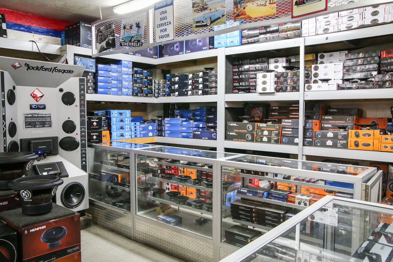 Interior of an electronics store, with shelves displaying car audio equipment. Speakers, amps, and other gear are on display.