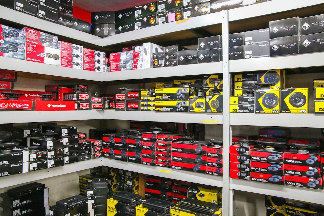 Shelves stocked with car audio equipment boxes. Red, black, yellow boxes fill the space.