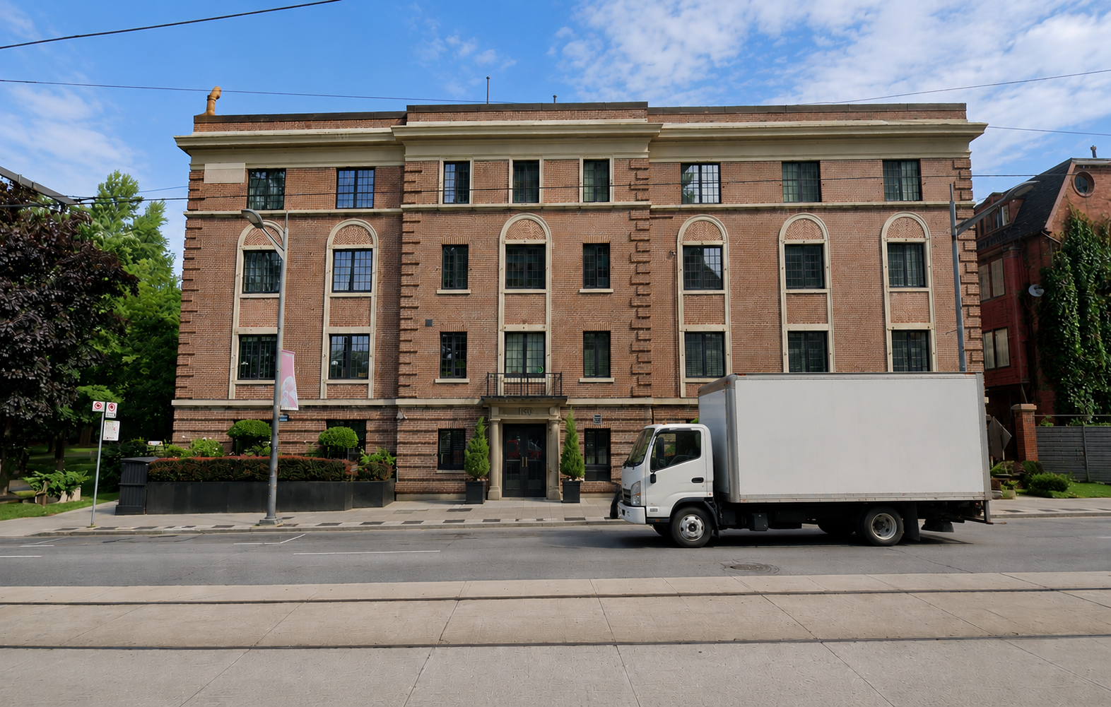 Brick apartment building with a white box truck parked in front on a city street