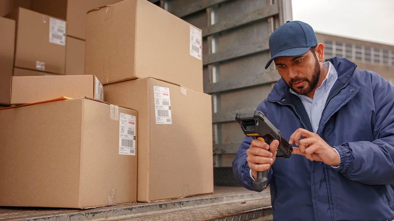 A man is using 49van app in front of a truck full of boxes.