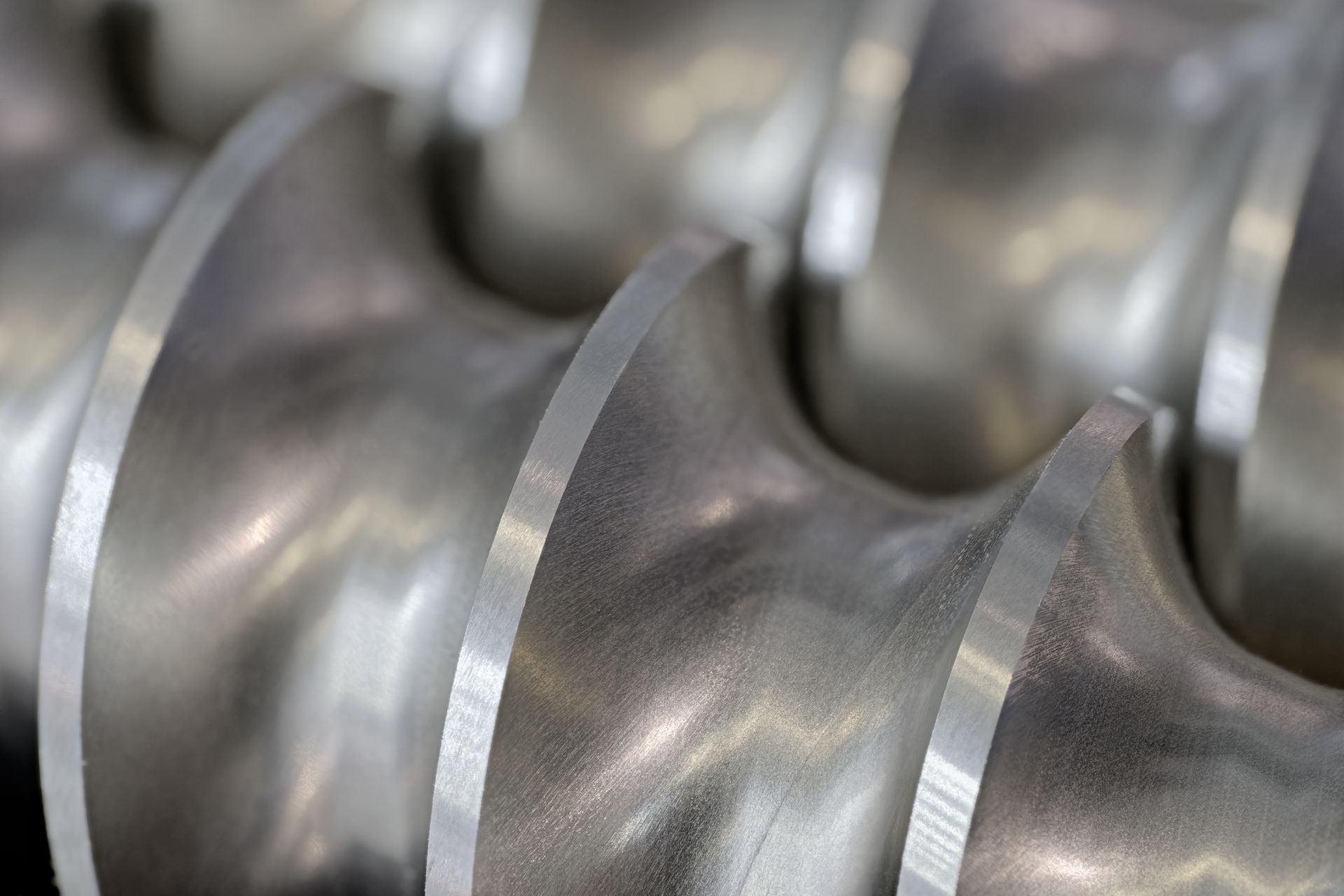 Close-up of shiny metal screw conveyor blades in an industrial machine
