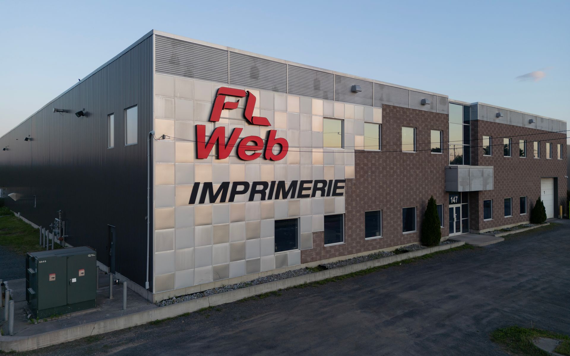 Extérieur du bâtiment de FL Web imprimerie avec un revêtement gris et un logo rouge