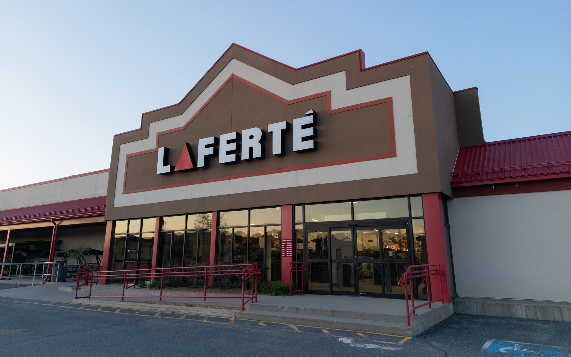 Extérieur du magasin LAFERTÉ : bâtiment marron avec garnitures rouges, vitrines et enseigne.