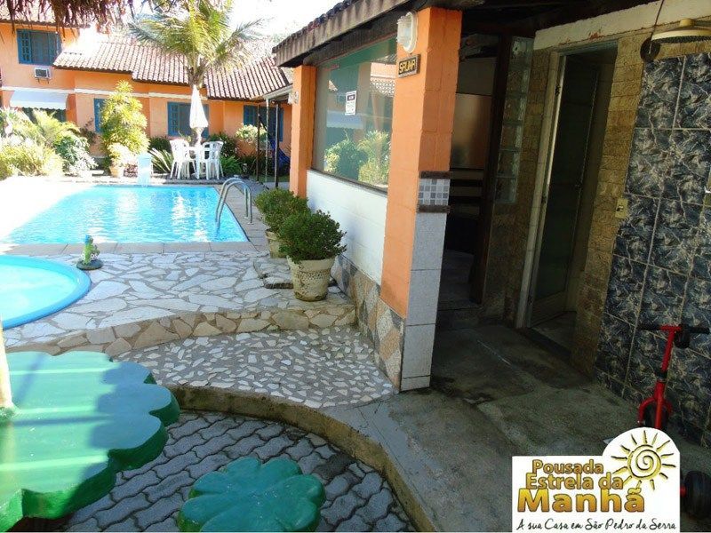 A swimming pool and tiled patio area at Pousada Estrela da Manhã in São Pedro da Serra.