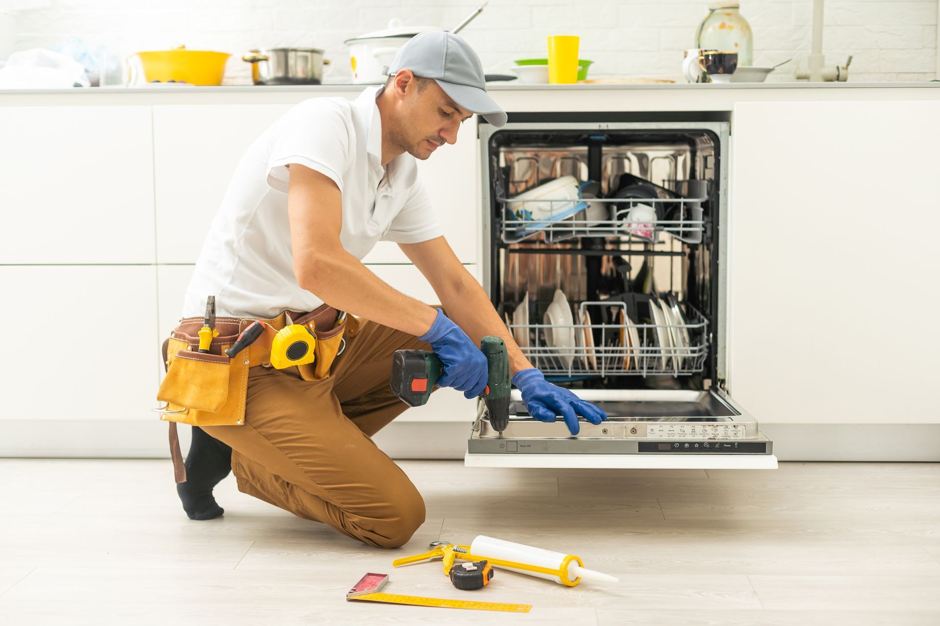 A man is fixing a dishwasher in a kitchen.
