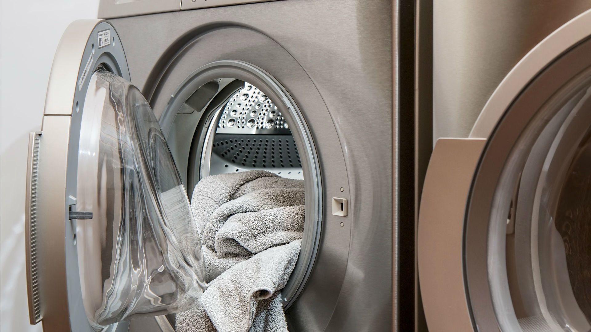 A washing machine is filled with clothes and the door is open.