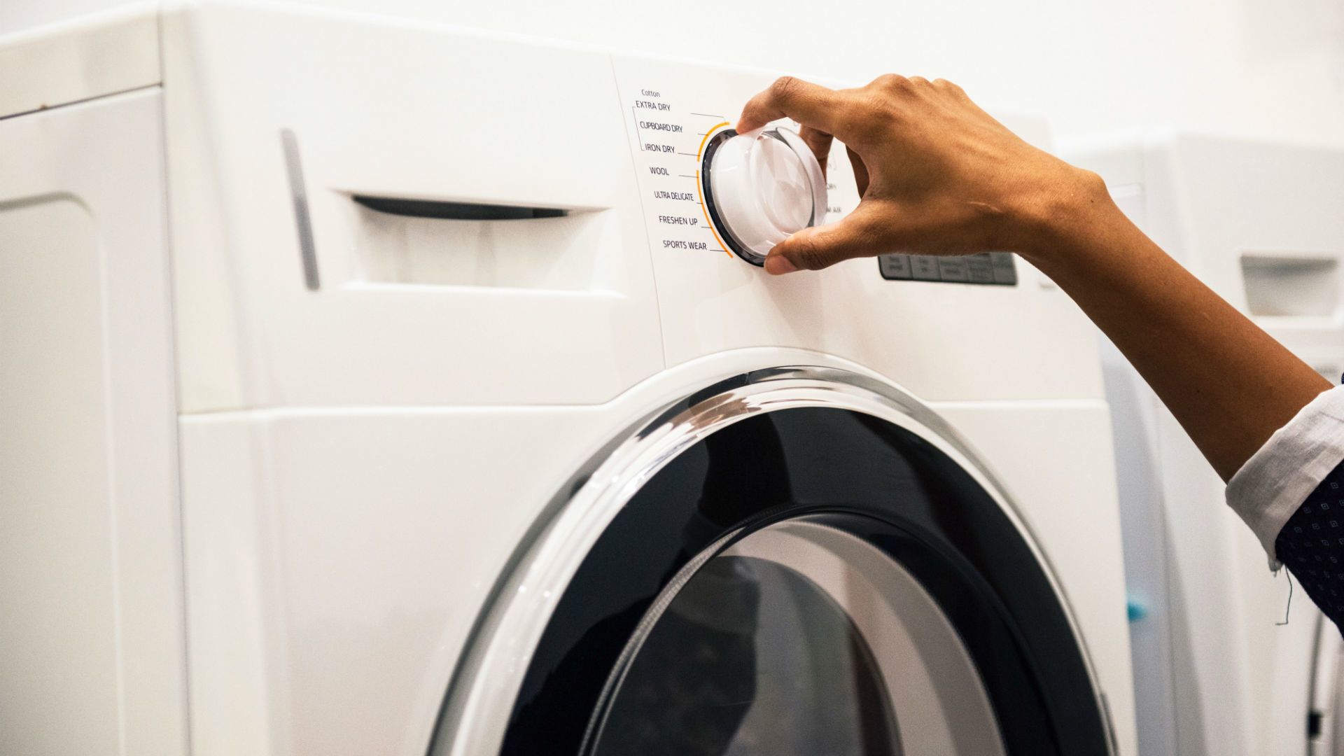 A person is pressing a button on a washing machine.