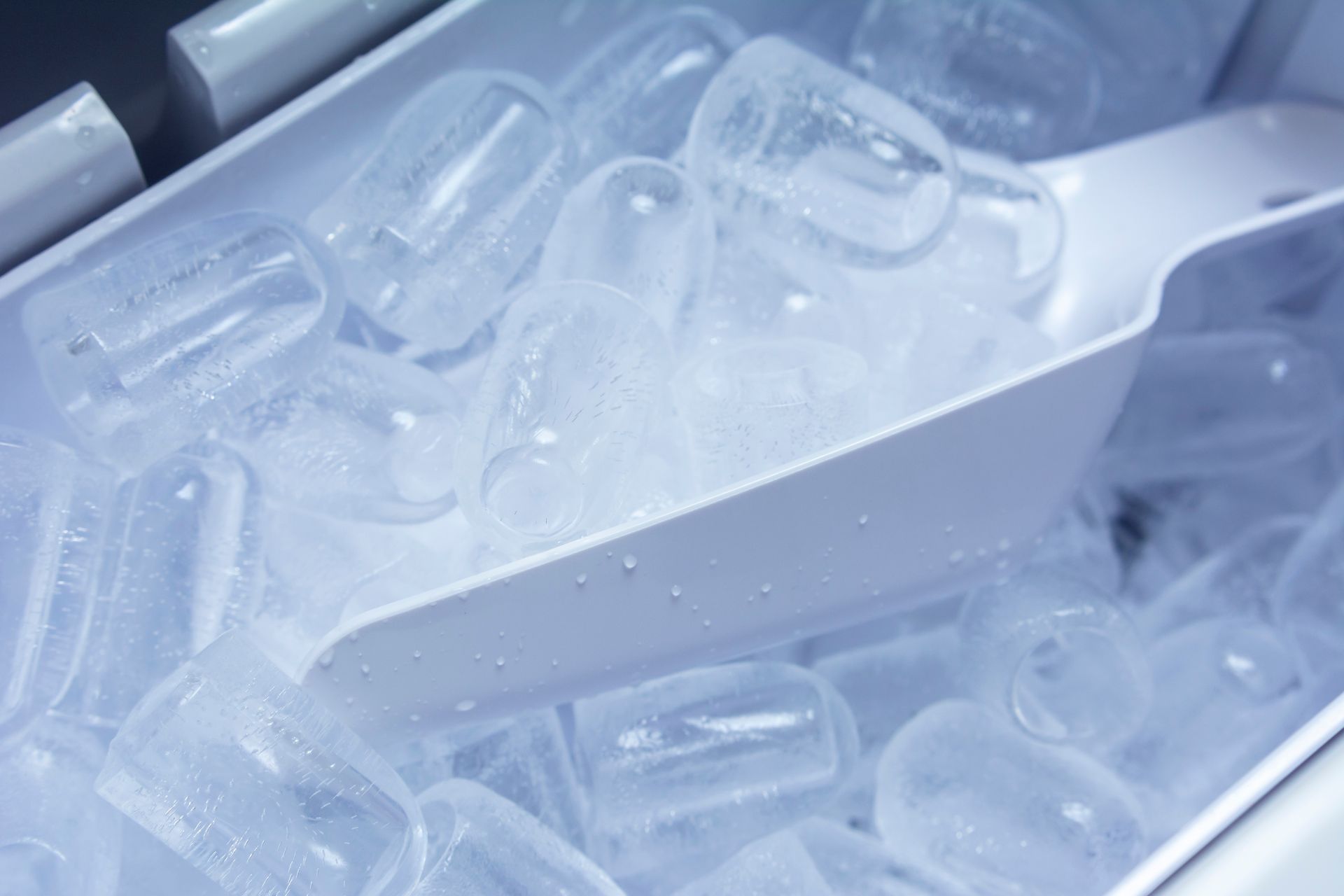 A bucket of ice cubes with a scoop in it.