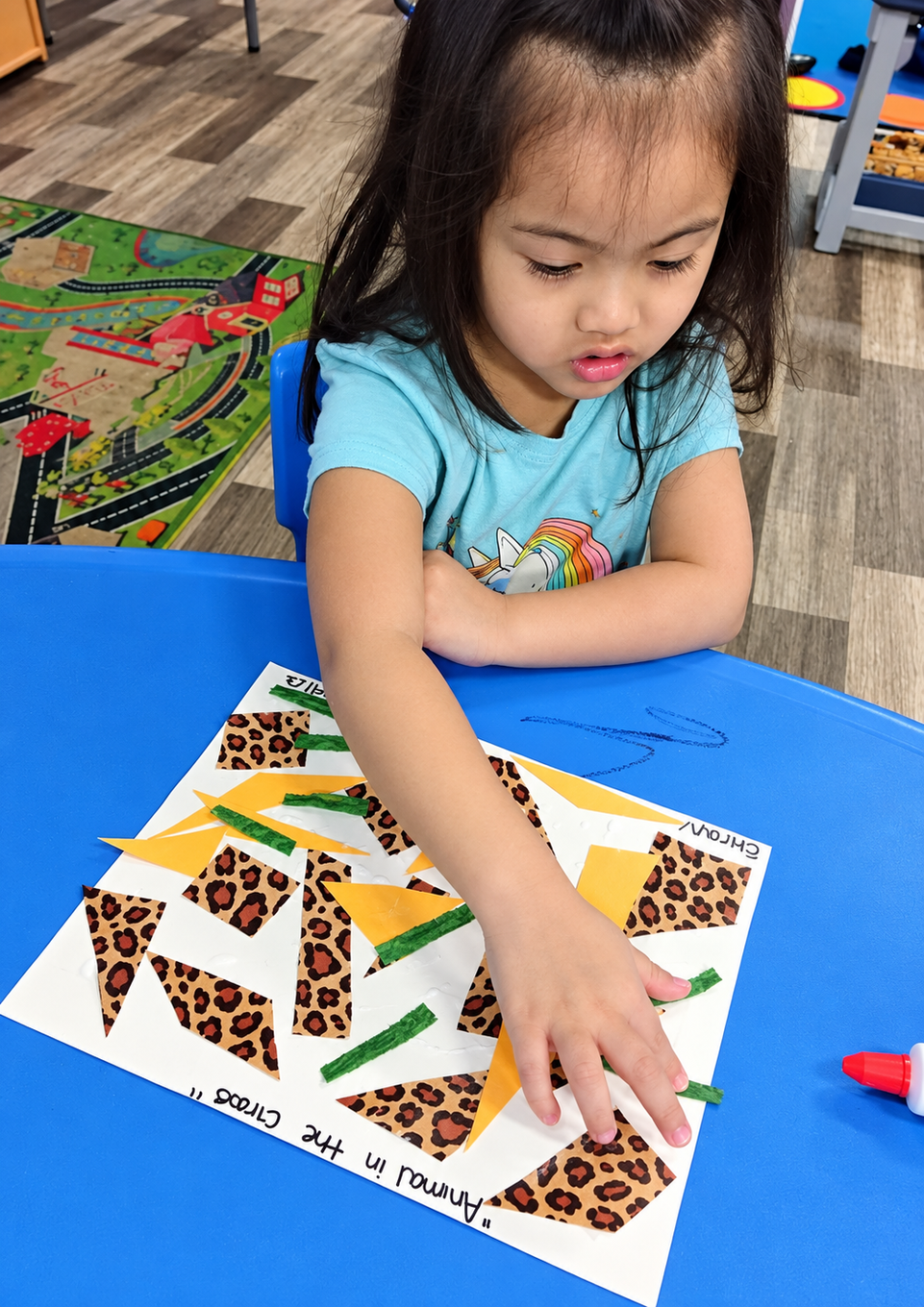 Child arranging a geometric puzzle at a blue table, focused on matching colorful triangle and leopard-print pieces