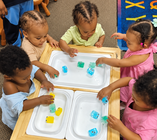 Children playing with colorful water toys at a sensory table in a classroom