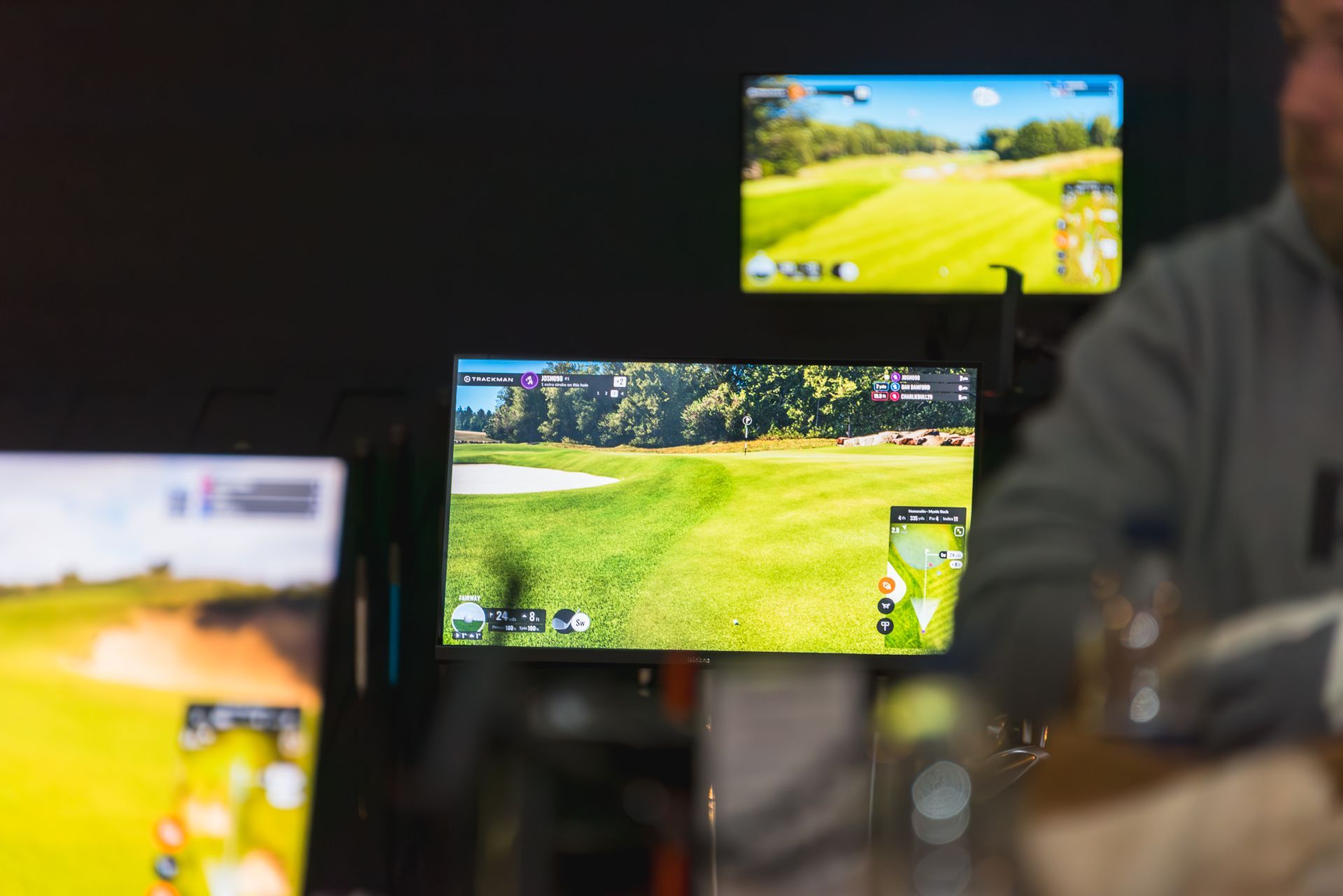 Multiple phone screens show a bright green golf course scene in a dim indoor setting