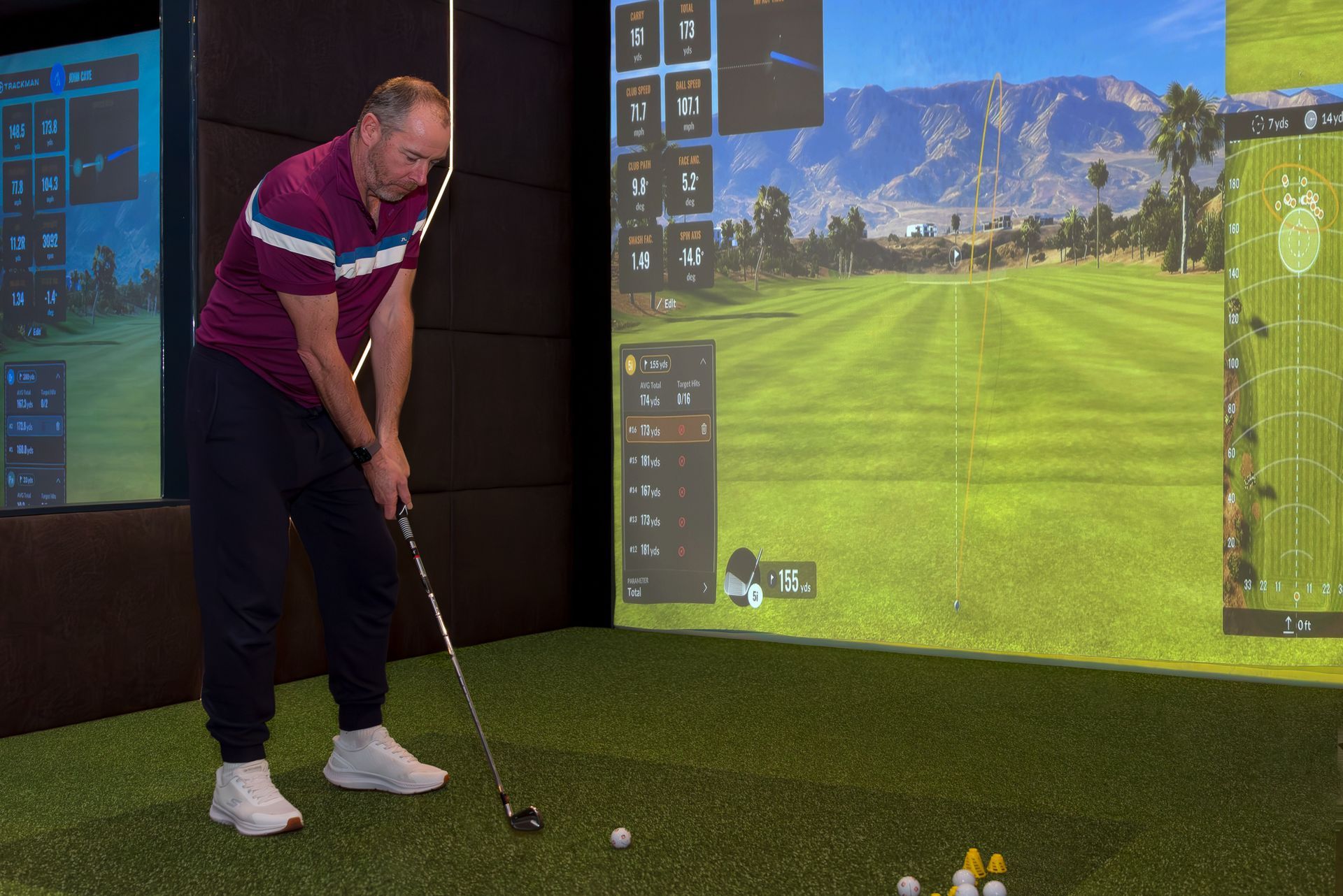 Golfer practicing indoors with a simulator screen showing a golf course