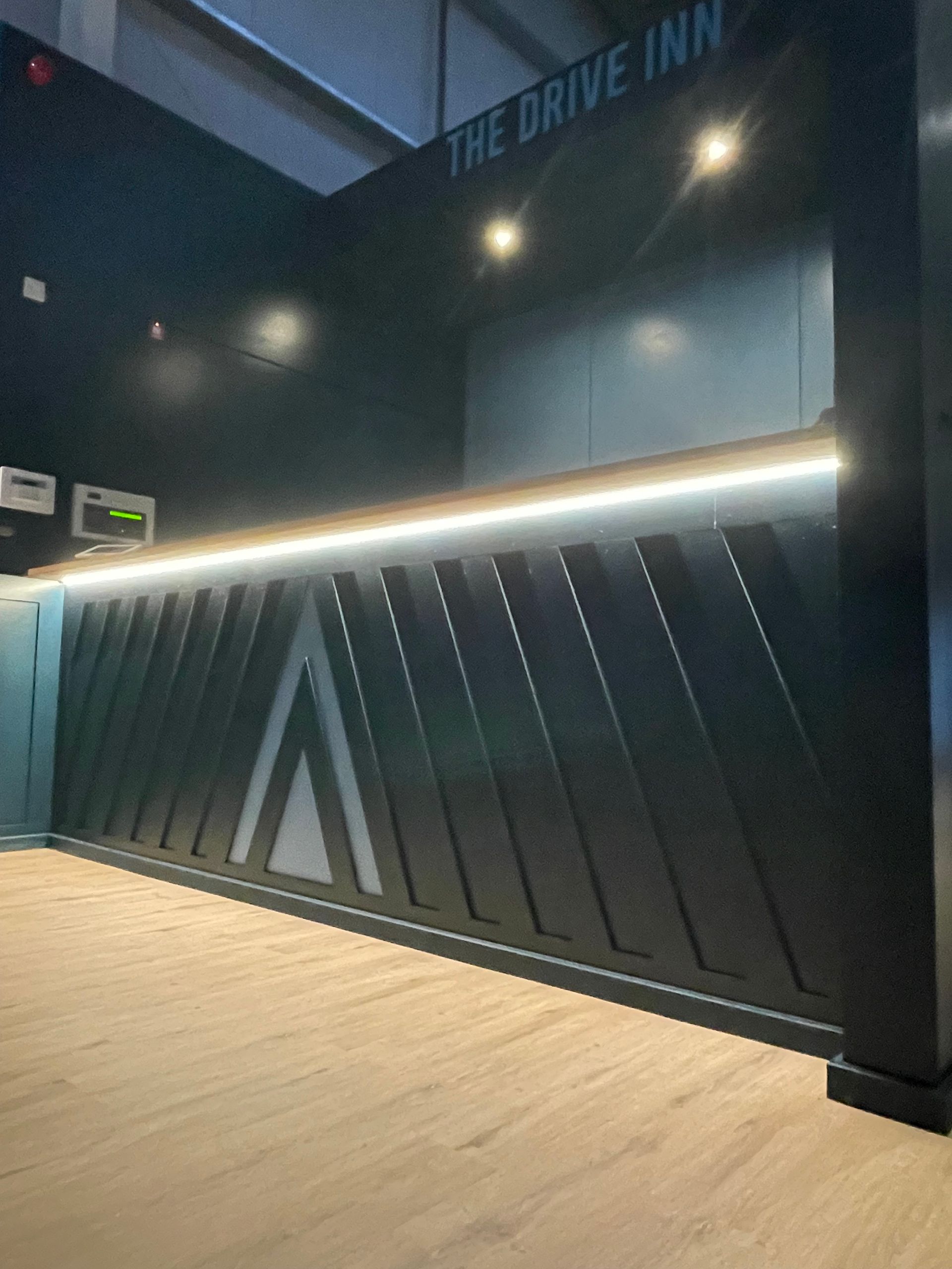 Modern drive-thru entrance with black slatted gate and illuminated strip at night