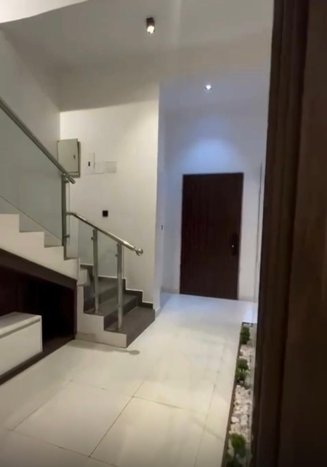 A hallway with stairs and a door in the background