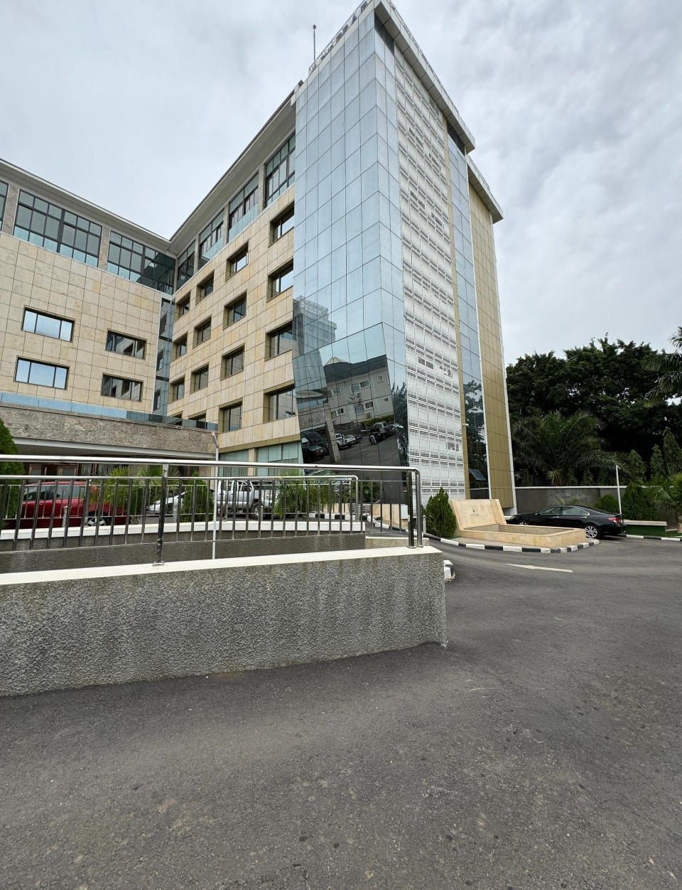 A large building with a lot of windows is sitting next to a parking lot.