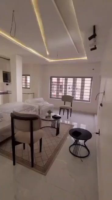 A room with two beds , a chair , a table and a television.