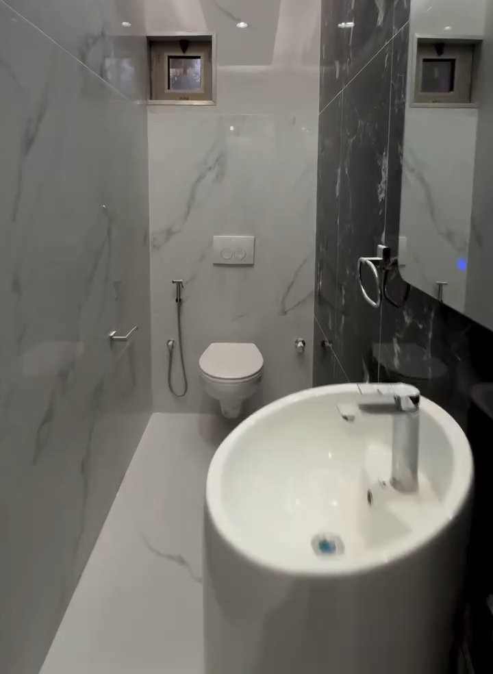 A bathroom with a toilet , sink and mirror