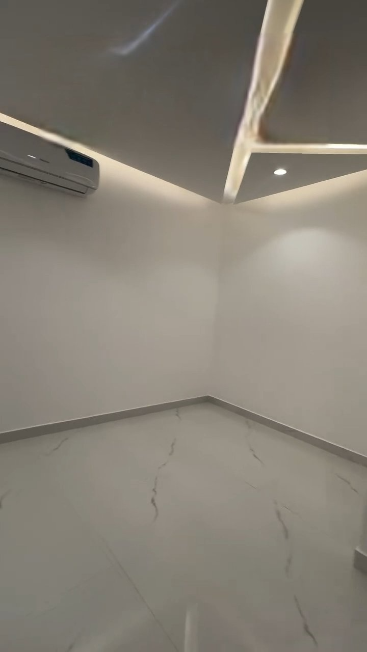 An empty room with a ceiling fan and a marble floor.