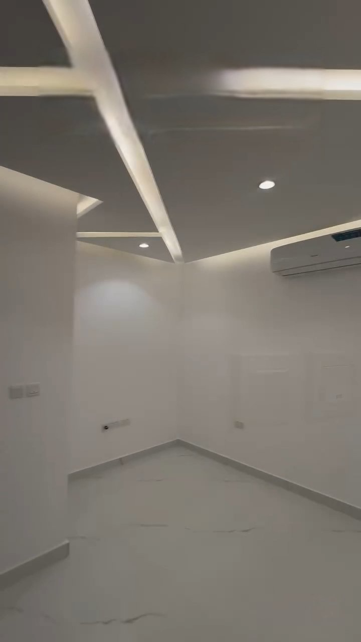 An empty room with a ceiling fan and a ceiling light.