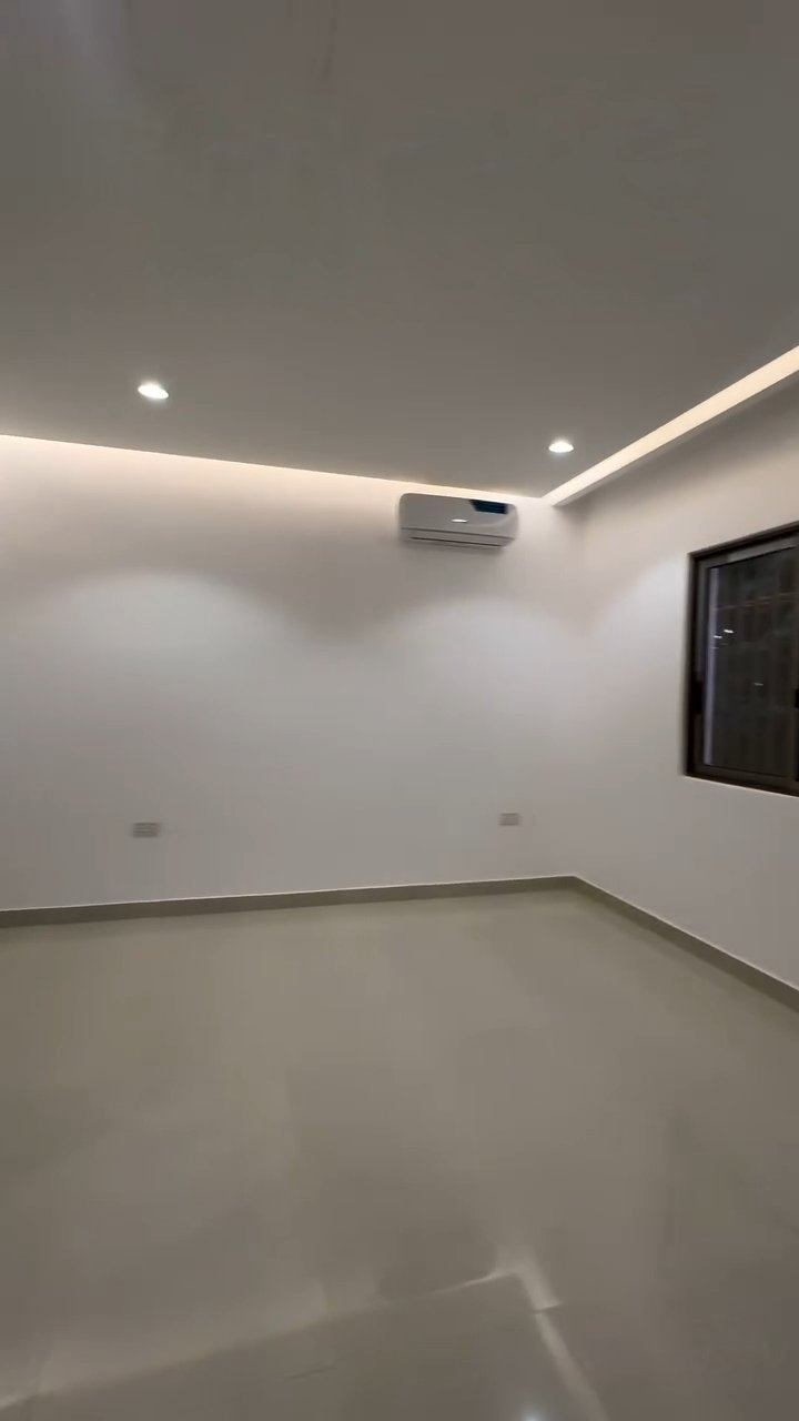 An empty room with a window and a ceiling fan.