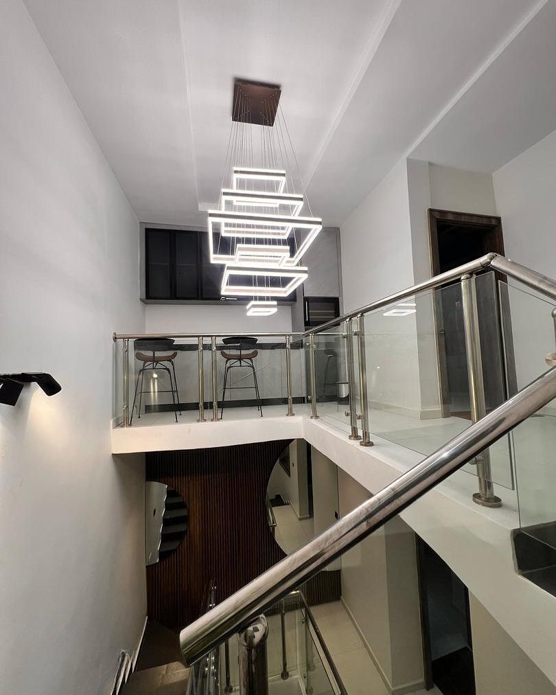 A staircase with a glass railing and a chandelier hanging from the ceiling.