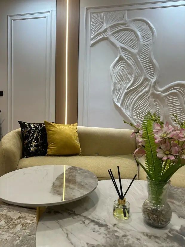 A living room with a couch , table , and vase of flowers.