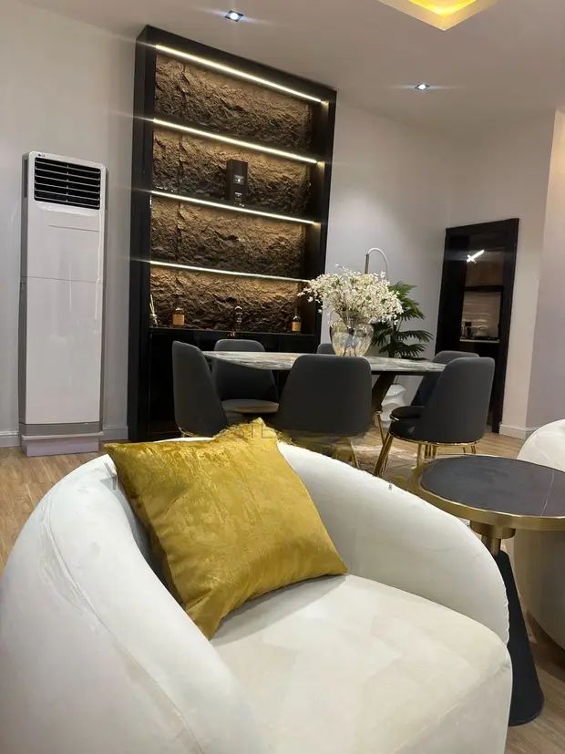 A living room with a white chair and a yellow pillow on it.