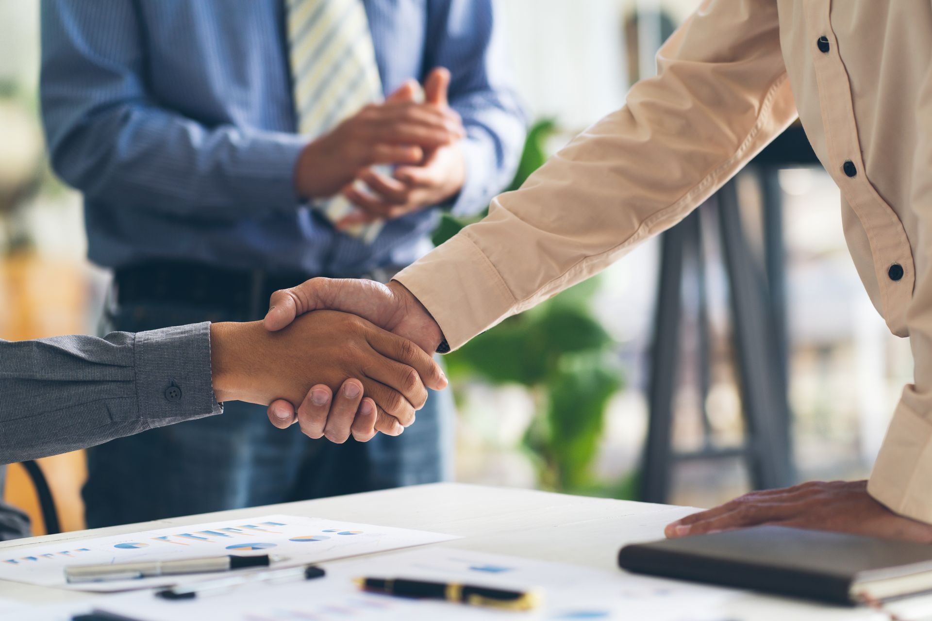“Two professionals shaking hands over blurred background.”