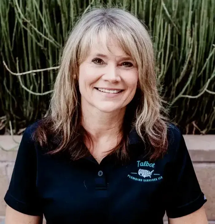 Smiling woman in a black polo shirt standing before tall green cacti