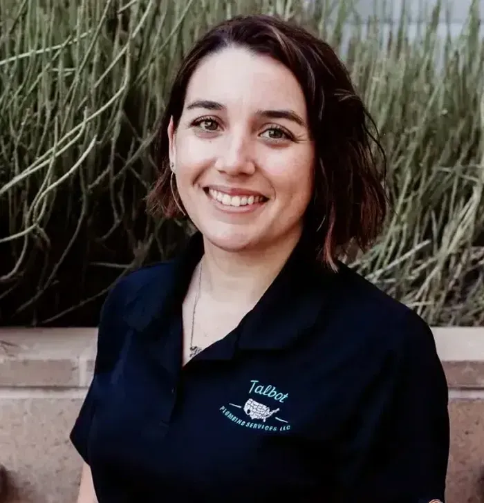 Smiling person in a navy polo shirt standing in front of tall grass.