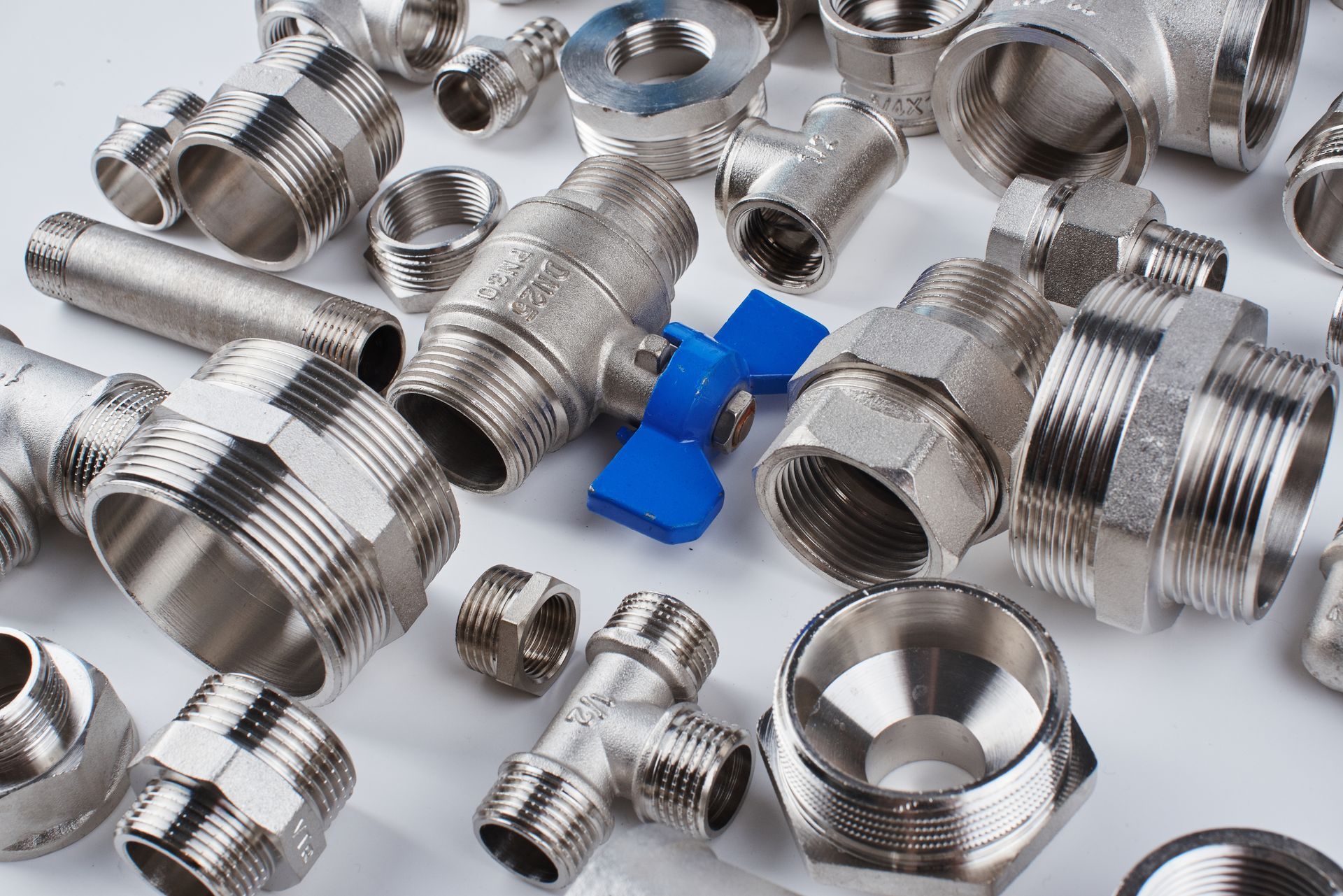 Assorted metal plumbing fittings, unions, and a blue-handled ball valve.