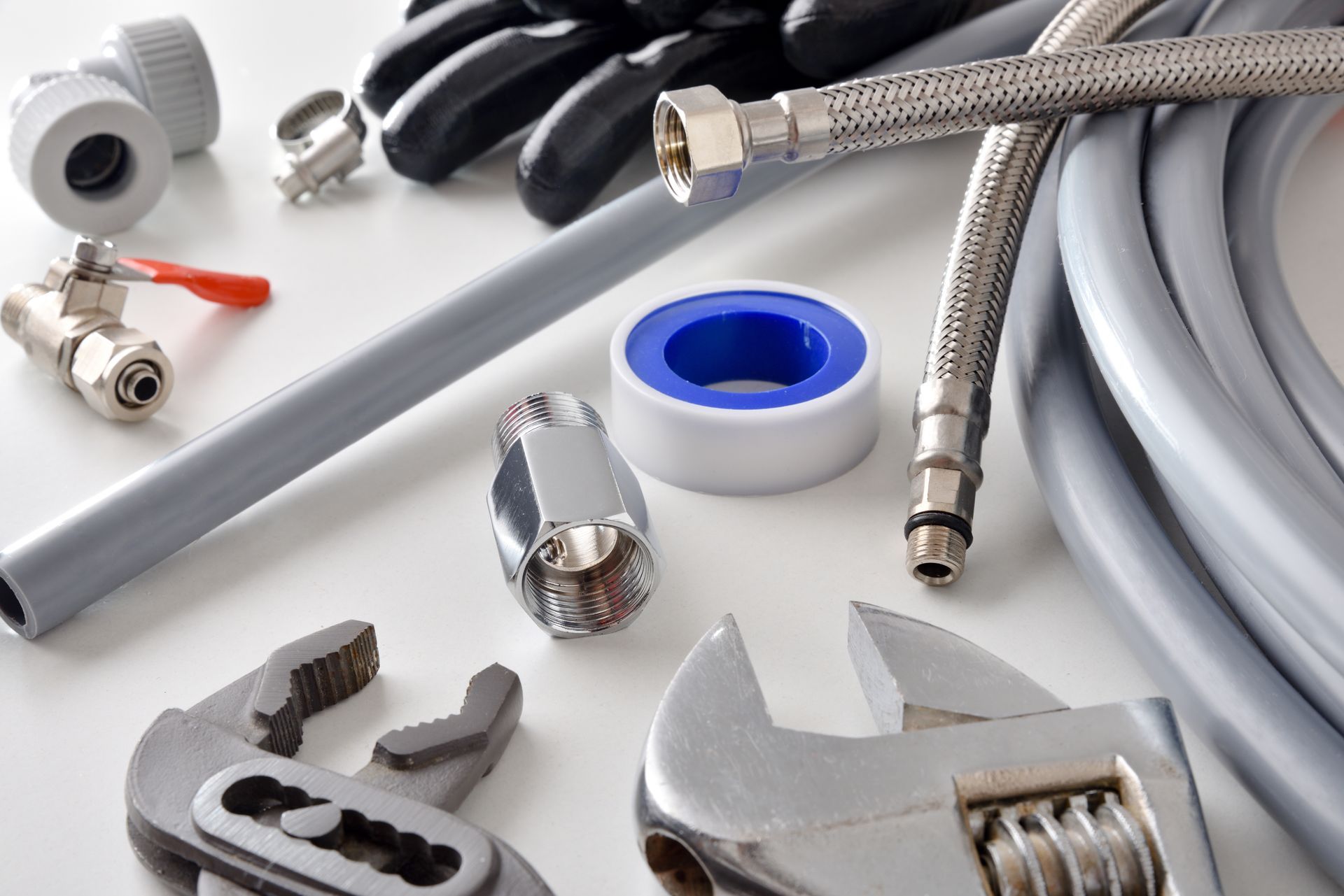 Assorted plumbing supplies and tools including valves, fittings, hoses, tape and wrenches
