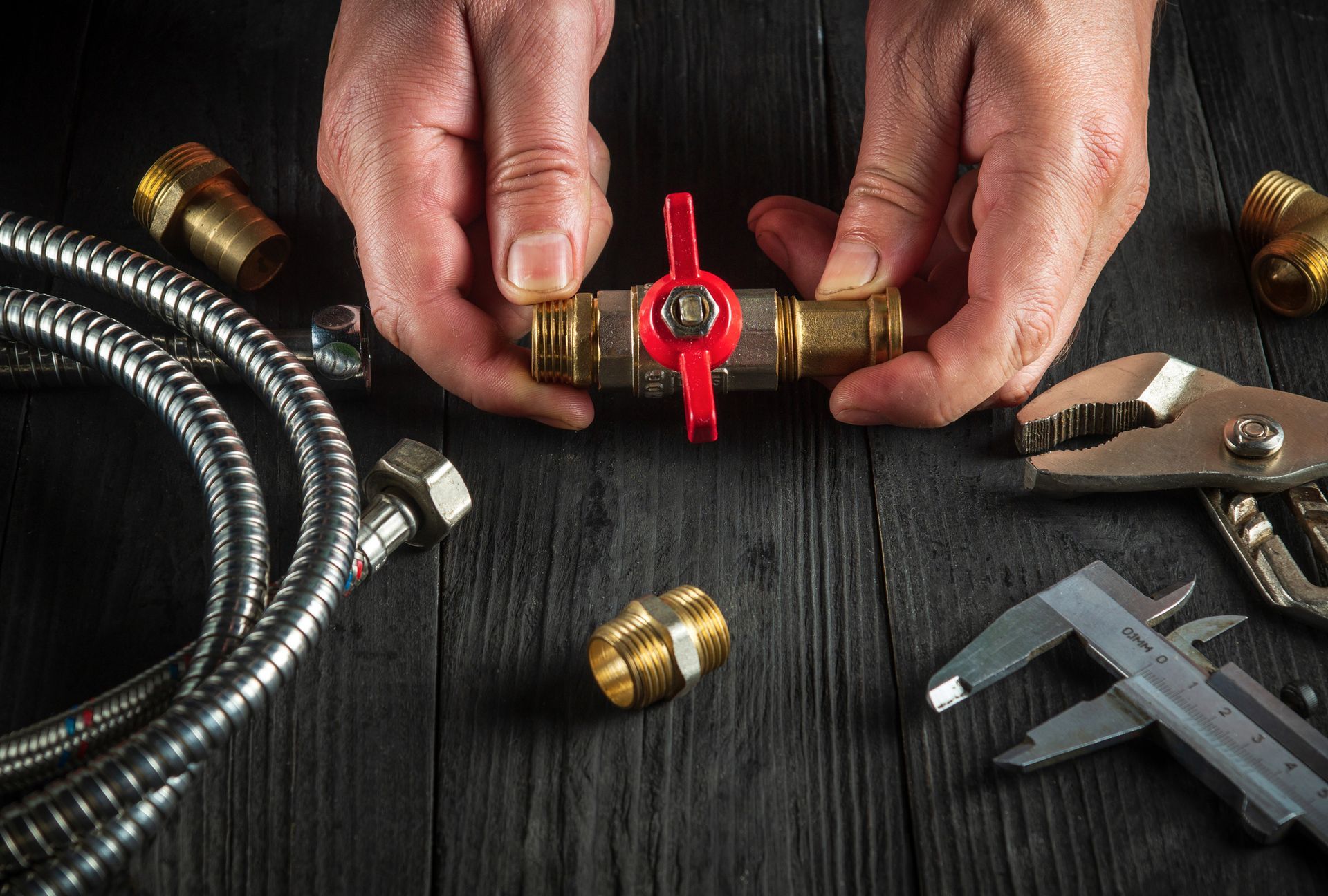 Close-up of master plumber’s hands, highlighting plumbing supply while repairing equipment.