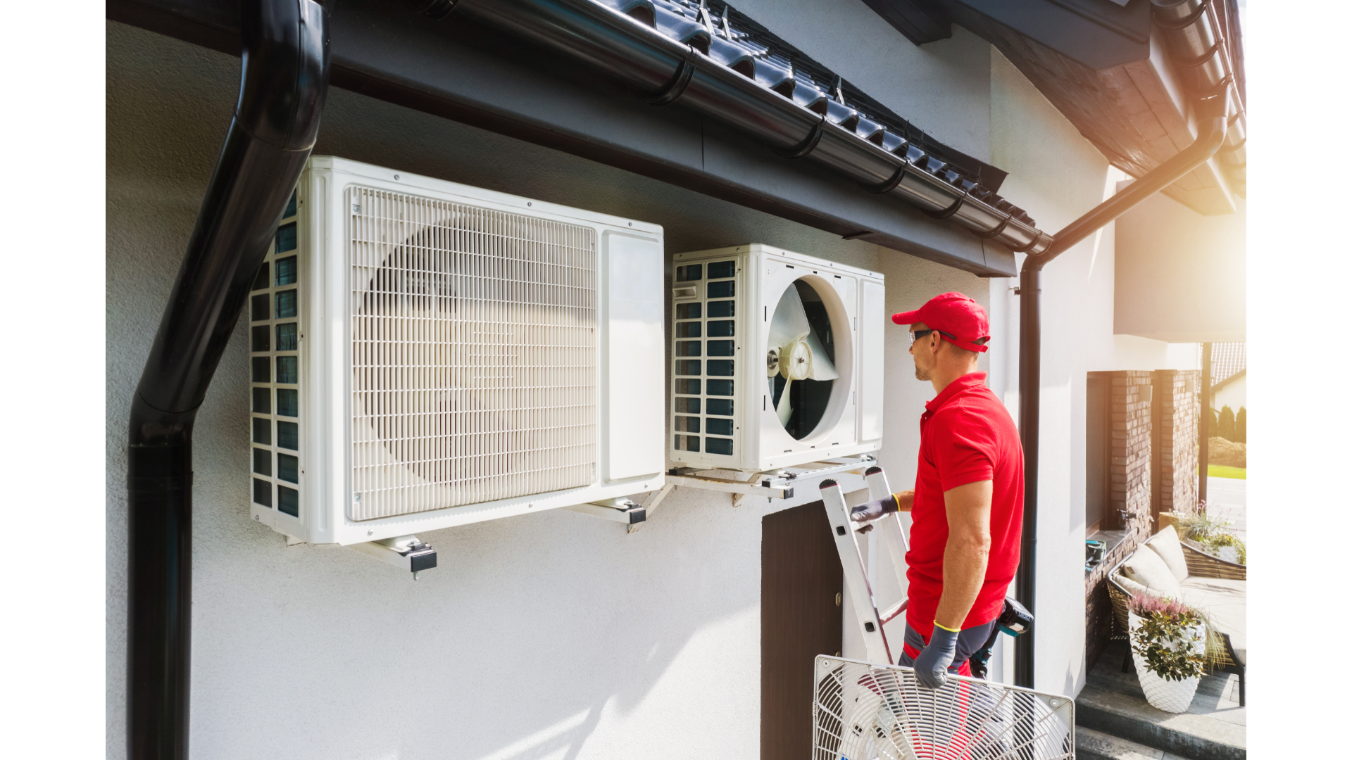 A man is installing air conditioners on the side of a building.