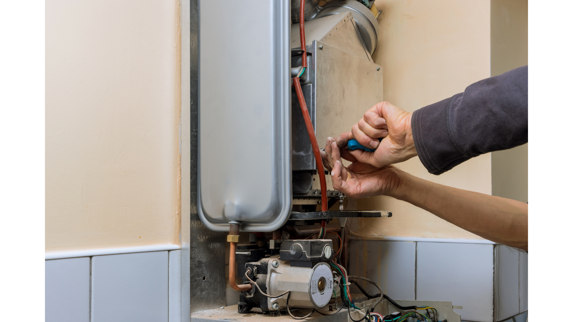 A person is fixing a boiler with a screwdriver.
