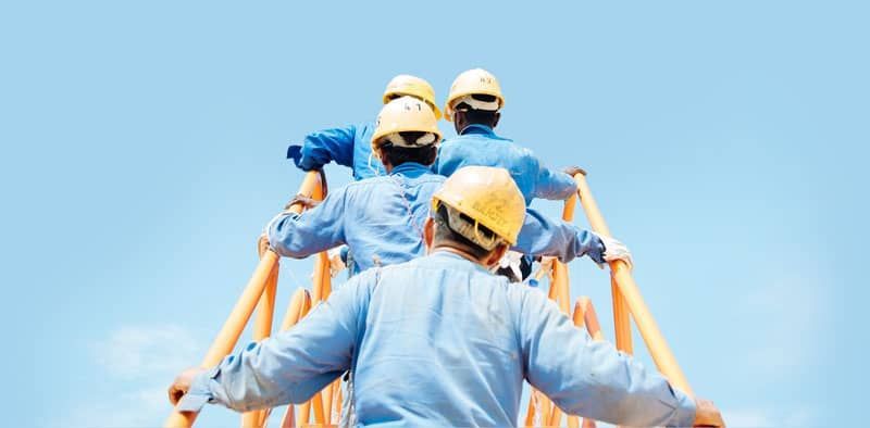 A group of construction workers are walking up a ladder.