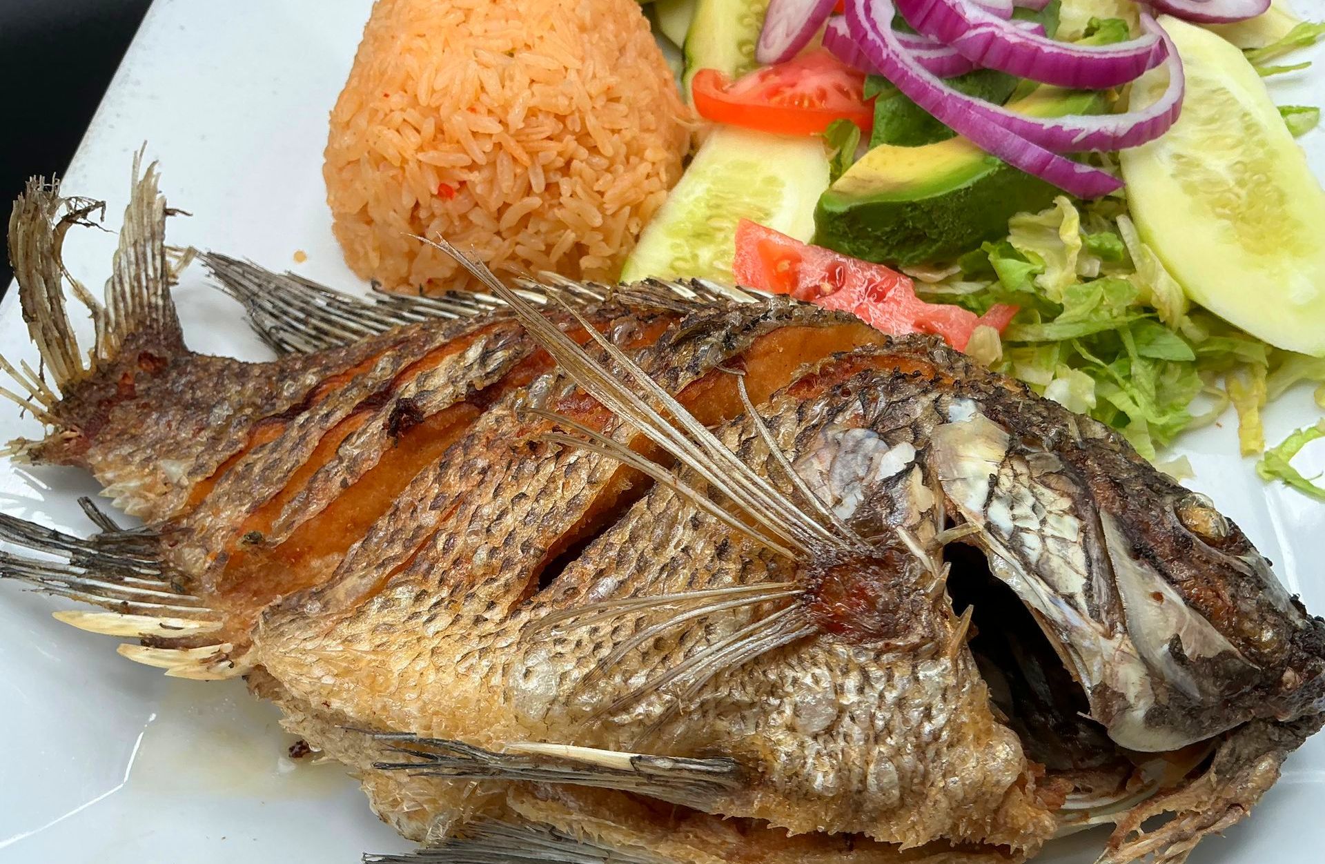Fried whole fish with rice and salad.