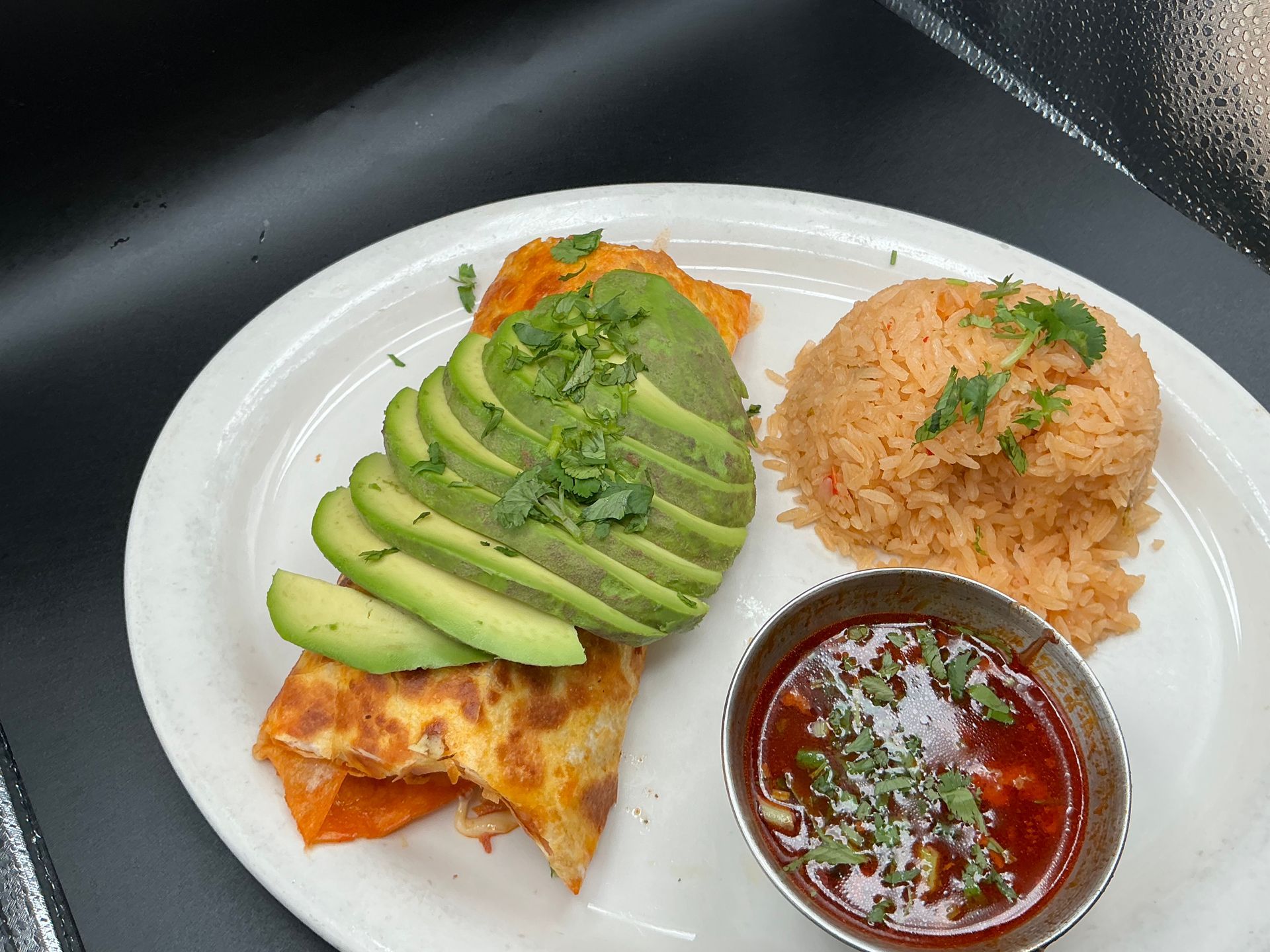 Mexican food plate with avocado, rice, and sauce.