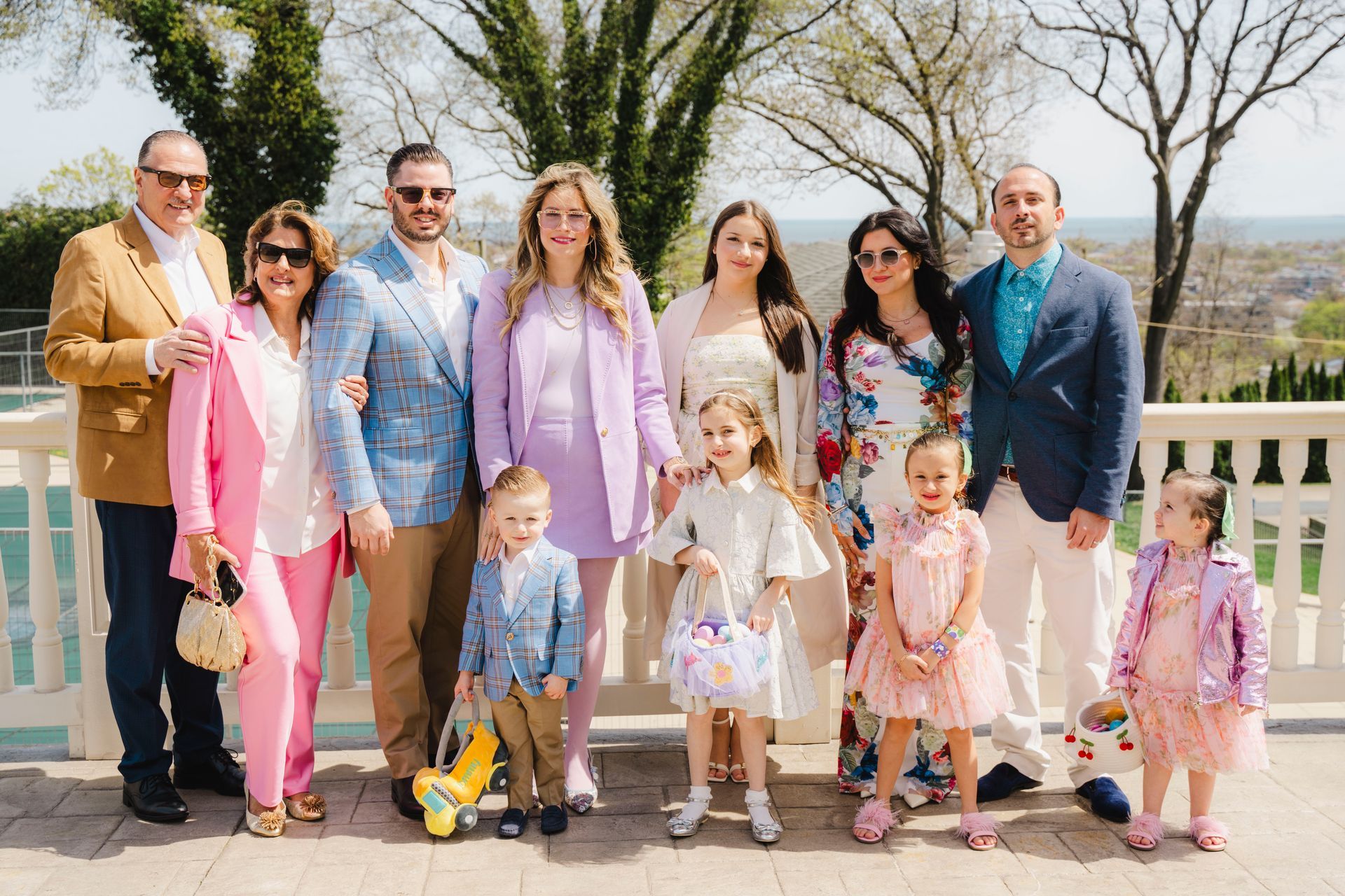 Family posing outdoors in spring, dressed in pastel colors, smiling at the camera.