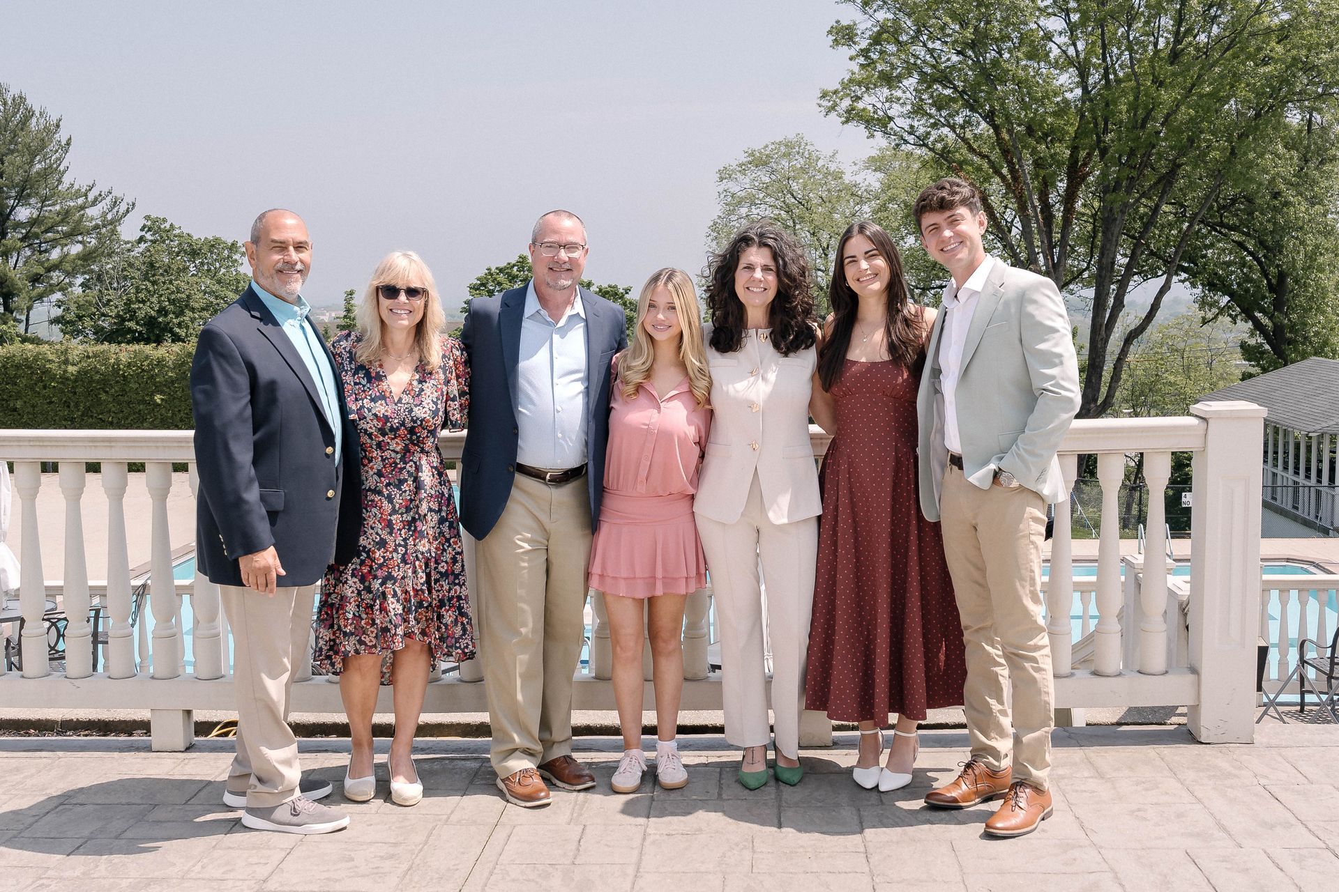 Family posing outdoors in spring, dressed in pastel colors, smiling at the camera.