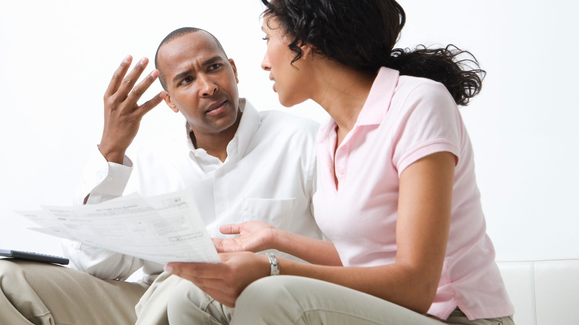 Man and woman, looking upset, review papers together in a white room.