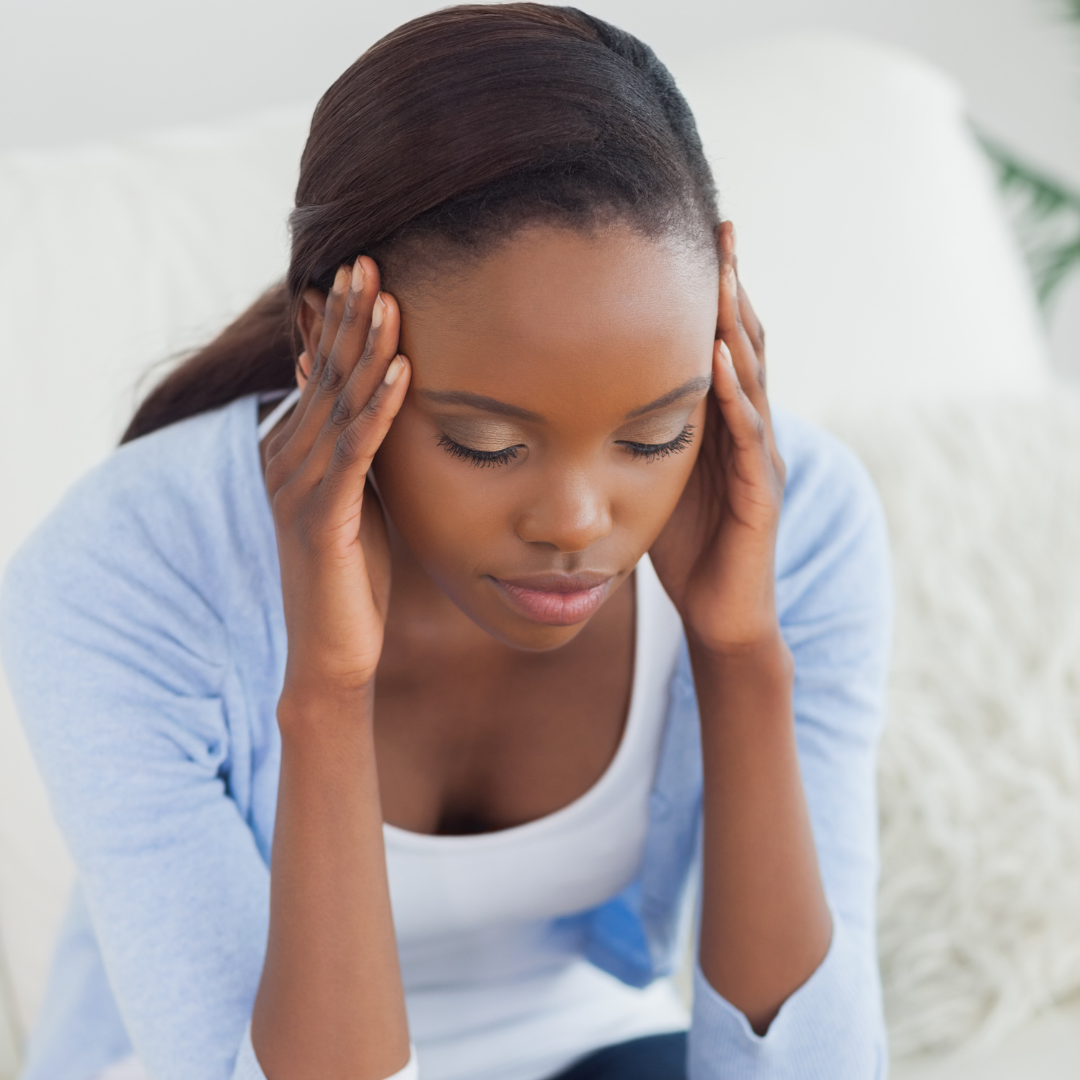 Woman with dark hair, wearing blue, holding head, appears to have a headache.