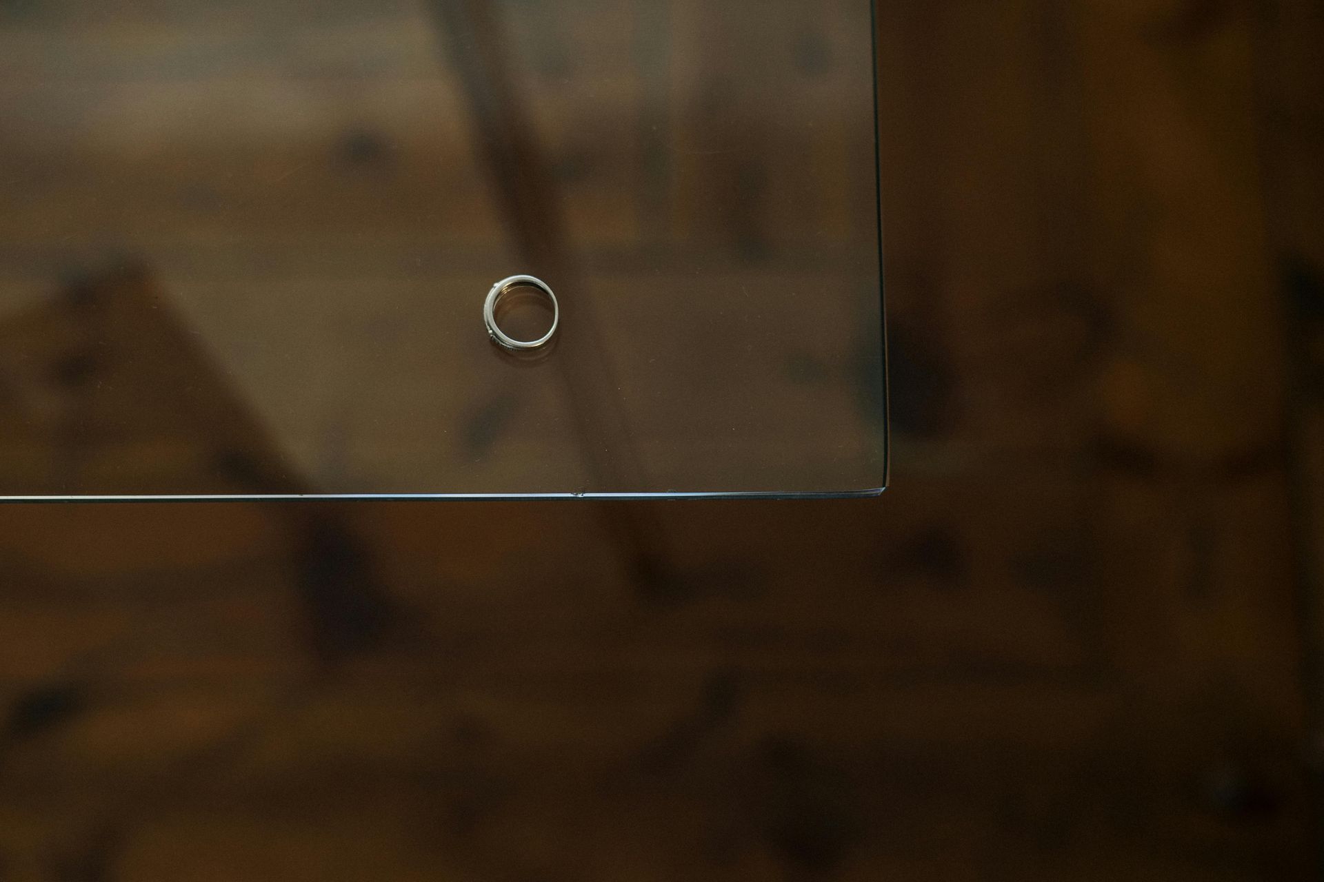 Clear glass tabletop with a silver ring. Background is wooden planks.