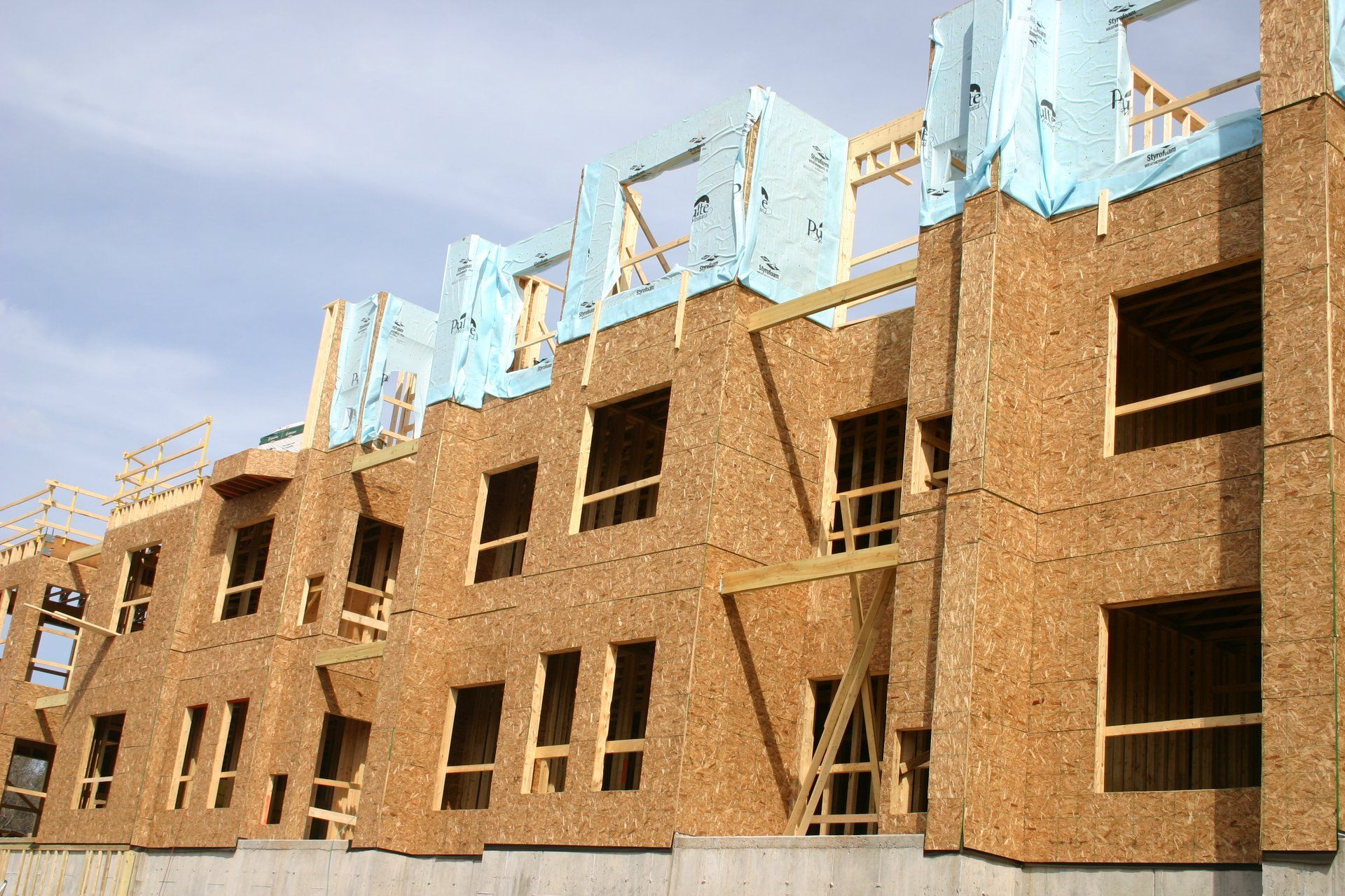 Partially built brick apartment building with open window frames and light blue rooftop structures