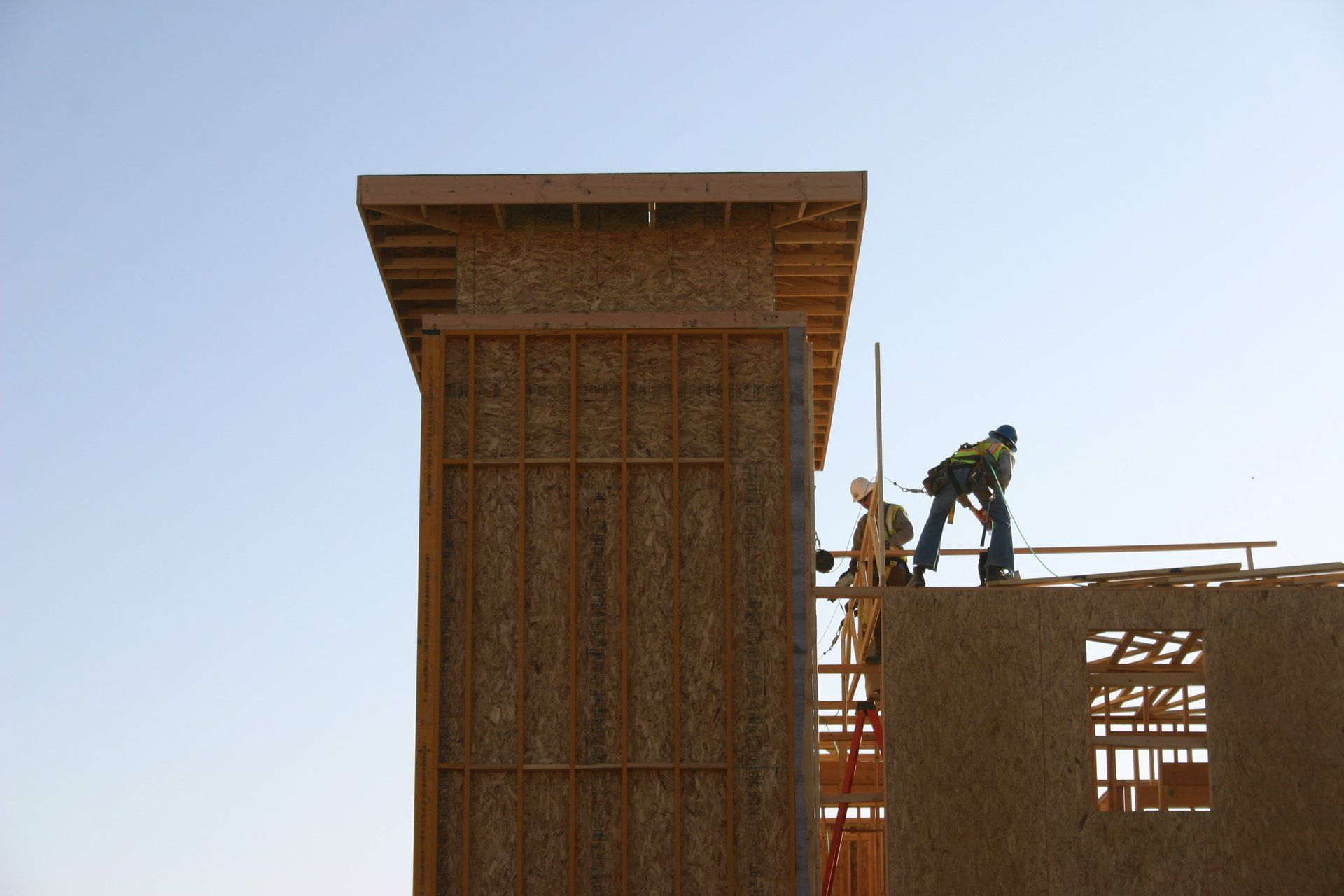 Construction workers on scaffolding beside a tall concrete building under construction