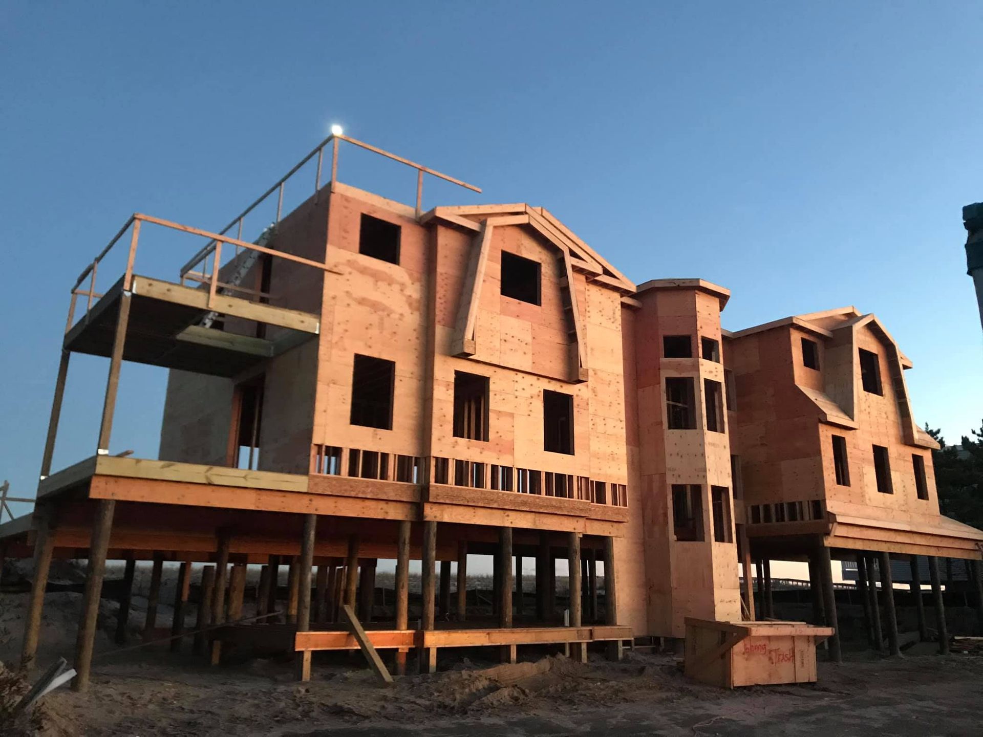 Partially built red-brick stilt house with open framing under a clear blue sky